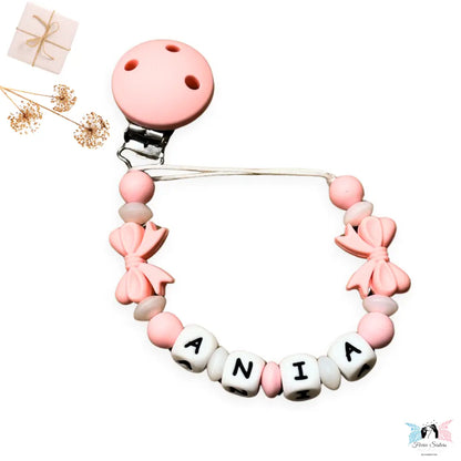 Attache tétine bébé fille personnalisée avec nœuds roses en silicone – accessoire fait main avec prénom, design élégant et sécurisé.